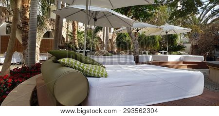 Empty Beds For Tan And Rest With Green Pillows And White Matresses In The Hotel Garden