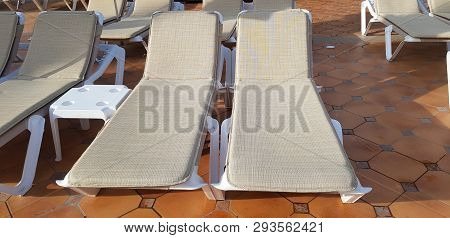 Two Chaise Lounges For Tan And Rest Stay Empty On Stone Floor