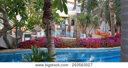 View On Outdoor Swimming Pool Surrounded By Palm Trees And Exotic Flowers With Two Elephant Statues 