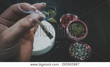 Smoking Medical Marijuana Joint. Marijuana Buds, Grinder And Ashtray On The Background