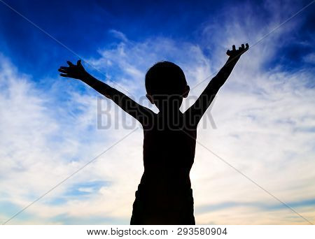 Happy Child Silhouette With Hands Up On The Sky Background