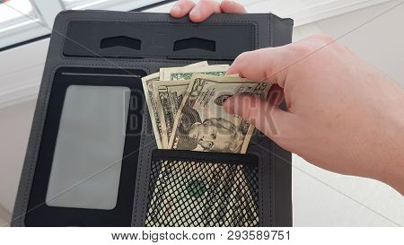 A Man Holds Black Folder With Paper Money In His Hands And Pulls Out Twenty Dollars Bill