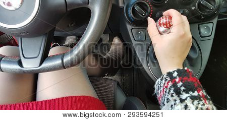 Woman In Red Mini Dress And Gray High Heels Boots Sitting On Drivers Seat Of Mini Sport Car Holding 
