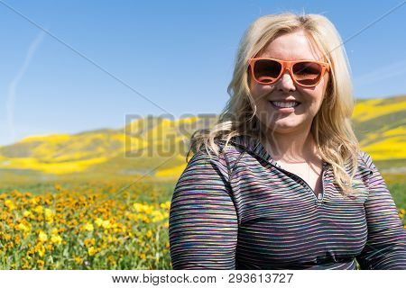 Blonde Woman Poses With Wildflower Field At Carrizo Plain National Monument In California. Wearing O