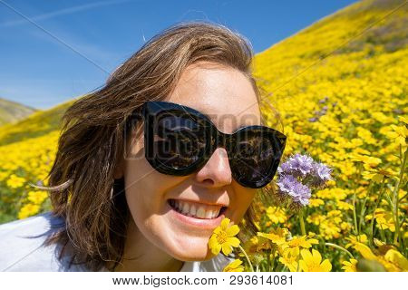 Woman Wearing Sunglasses Sits And Poses In A Field Of Yellow Wildflowers At Carrizo Plain National M