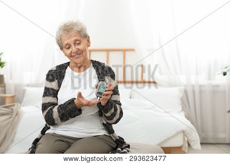 Senior Woman Using Digital Glucometer At Home. Diabetes Control