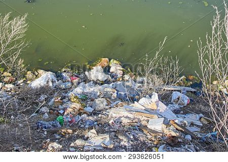 Garbage Thrown To The Bank Of The River, The Topic Of Environmental Pollution