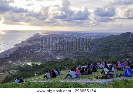 Yogyakarta, Indonesia - April 2, 2019 People Sitting On The Ground And Watch For Sun Set On Paraglid