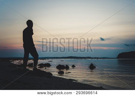 Man Hiking Silhouette In Mountains, Sunset And Ocean. Male Hiker With Backpack On Top Of Mountain Lo