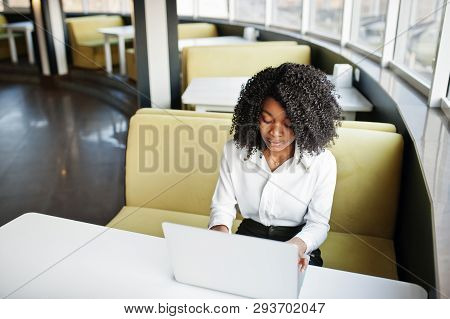 Сheerful Business African American Lady With Afro Hair, Wear White Blouse Sitting At Table And Work