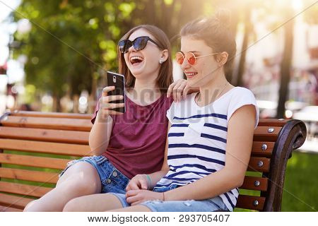 Loyal Happy Friends Feel Good Near Each Other In The Park. Beautiful Cheerful Girls Read Funny Unpre
