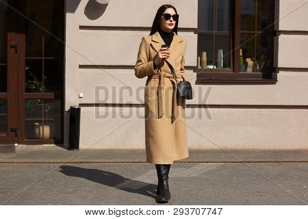 Portrait Of Young Amazing Woman Standing In Front Of Popular Restaurant, Wears Stylish Sunglasses, M