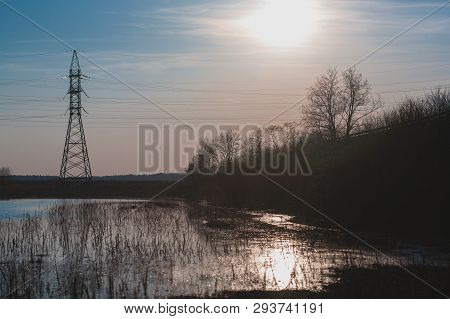 Spring Sunset Over High Voltage Wires And Flooded Meadow.