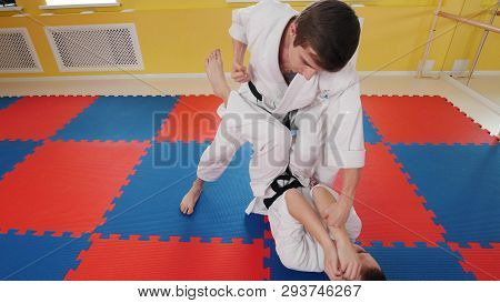 Two Athletic Men Training Their Aikido Skills In The Studio. A Man Lying On The Floor And Protecting