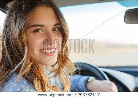 Back View Of Attractive Woman In Car, Sitting At Wheel, Turning And Looking At Passengers In Back Se