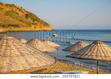 Straw Umbrellas On The Beach With Sea And Sky In The Closeup Background.
