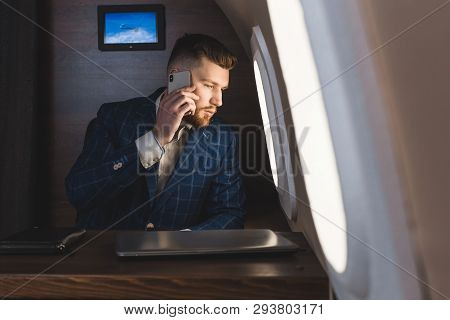 Young Attractive And Successful Businessman Talking On The Phone And Working While Sitting In The Ch