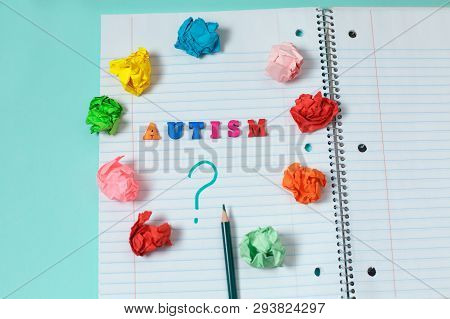 Autism Colorful Word From Color Wooden Letters On Notebook Page And Question Mark With A Pencil Surr
