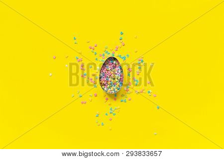 Egg Shape Form And Scattering Multicolored Confectionery Topping Dressing On Yellow Paper. Concept E