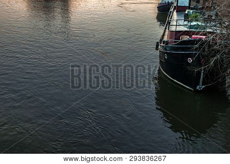 A Boat That Is Parked On The Banks Of The River Thames At Sunset