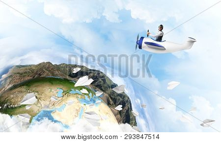 Pilot In Leather Helmet Driving Propeller Plane On Background Of Blue Cloudy Sky. Traveling Around T