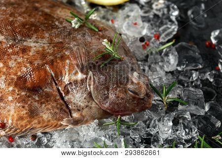 Raw Lemon Sole Fish On Ice With Herbs And Lemon Wedges
