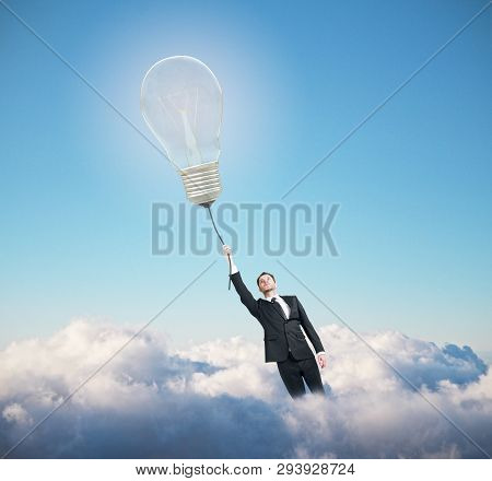 Businessman With Glowing Lamp Flying On Blue Ske With Clouds Background. Idea Concept