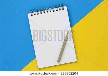 Blank Spiral Notebook With A Blank Page And Pencil, On A Blue And Yellow Diagonal Background