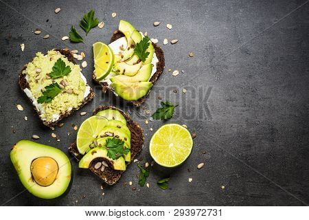 Sandwiches With Avocado And Cream Cheese With Grain Bread And Seeds. Black Slate Background, Top Vie
