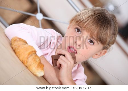 junges Mädchen mit einem Croissant und Tafel Schokolade
