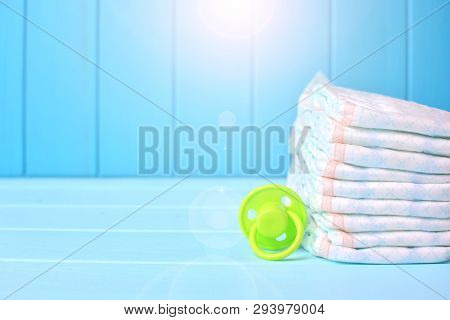 Baby Accessories Background. Pile Of Diapers With Dummy. Copy Space.