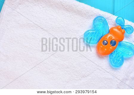 Baby Accessories Background. Blue Butterfly Teether On A White Towel. Copy Space.