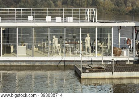 Floating River Restaurant On The River Bank. Large White Mannequins In The Windows. Creative Idea