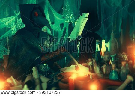 The plague doctor is working at his desk, inventing a cure for bubonic plague. The atmosphere of mysticism. Historical reenactment. Halloween. 