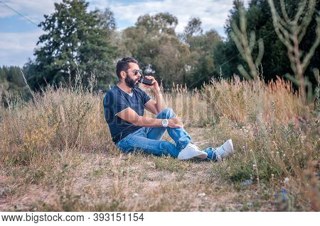 Confident Vape Man Resting On The Nature And Smoking E-cigarette. Alternative To Smoking.