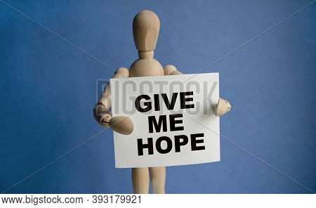 The Wooden Man Holds A White Sign With The Text Give Me Hope In His Hands. The Content Of The Letter