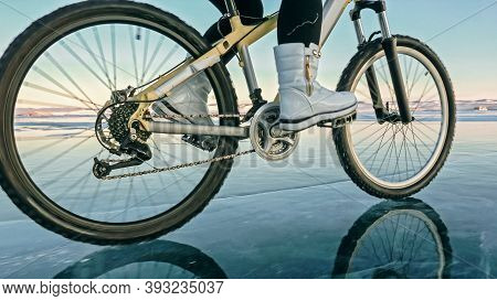 Woman Is Riding Bicycle On The Ice. Tires On Bike Are Covered Wi