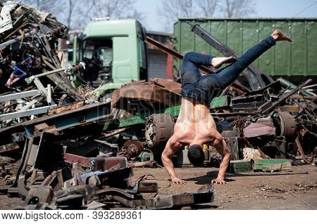 Young Athletic Man Doing Handstand At Industrial Junkyard