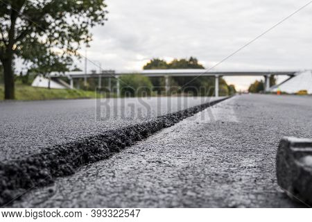 A Large Layer Of Fresh Hot Asphalt. Layer Of Asphalt Raw Material In A Shallow Depth Of Field. Rolle