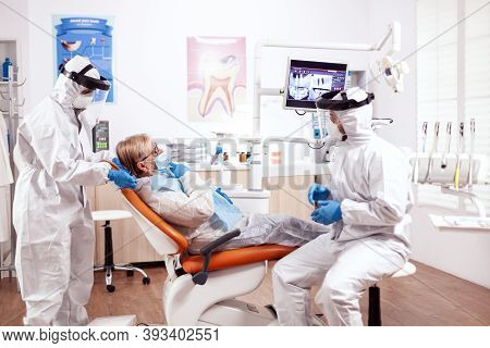 Dentist Wearing Equipment Agasint Coronavirus Dicussing About Teeth Hygiene With Senior Patient. Eld