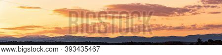 Styrian Alps Covered With Snow In Orange Light Of Sunset. View At Mountain Chain Of Lavanttaler Alps