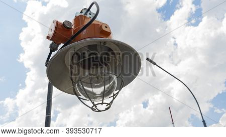 Industrial Explosion Proof Lantern On The Background Of The Classic Blue Sky With Clouds.