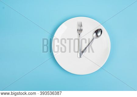 Top View White Ceramic Plate With Knife, Spoon And Fork On Blue Background. Intermittent Fasting, Ke