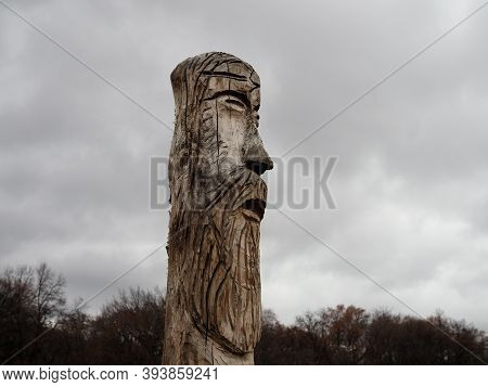 Wooden Idol Of The Slavic God Perun Near The Path In The Forest. Gloomy Forest In The Background And