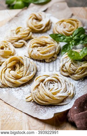 Pasta Alluovo, Tagliatelle Or Fettuccine. Round Balls Of Raw Pasta On The Wooden Cutting Board On Bl