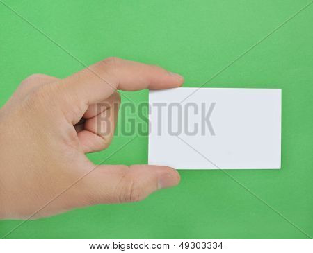 Cartão de visita em branco na mão sobre fundo verde