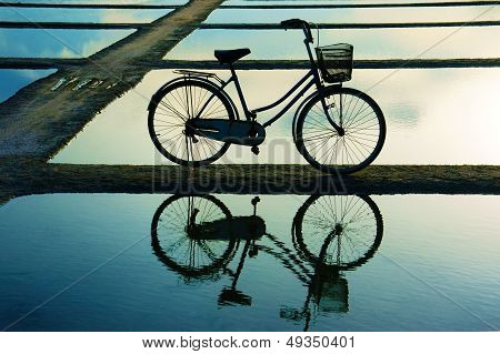 Fahrrad zuzwinkern auf Wasseroberfläche bei Sonnenuntergang