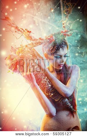 Art project. Beautiful girl in the image of a wild deer stands in a deserted forest. 