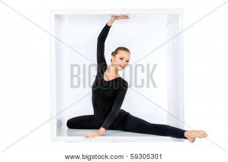 Modern bellet dancer posing with a cube at studio. Plastic body concept. Isolated over white.