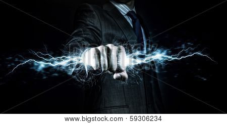 Businessman holding lightning in fist. Power and control
